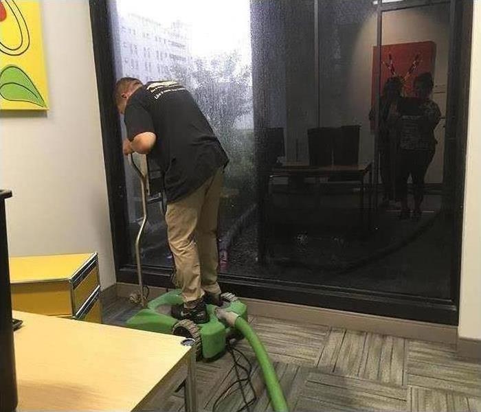 SERVPRO employees using vaccum to clean up water damage to carpet in a office building near Orlando, FL 