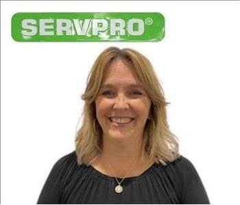 Lori, female, SERVPRO employee in dress shirt in front of green SERVPRO logo